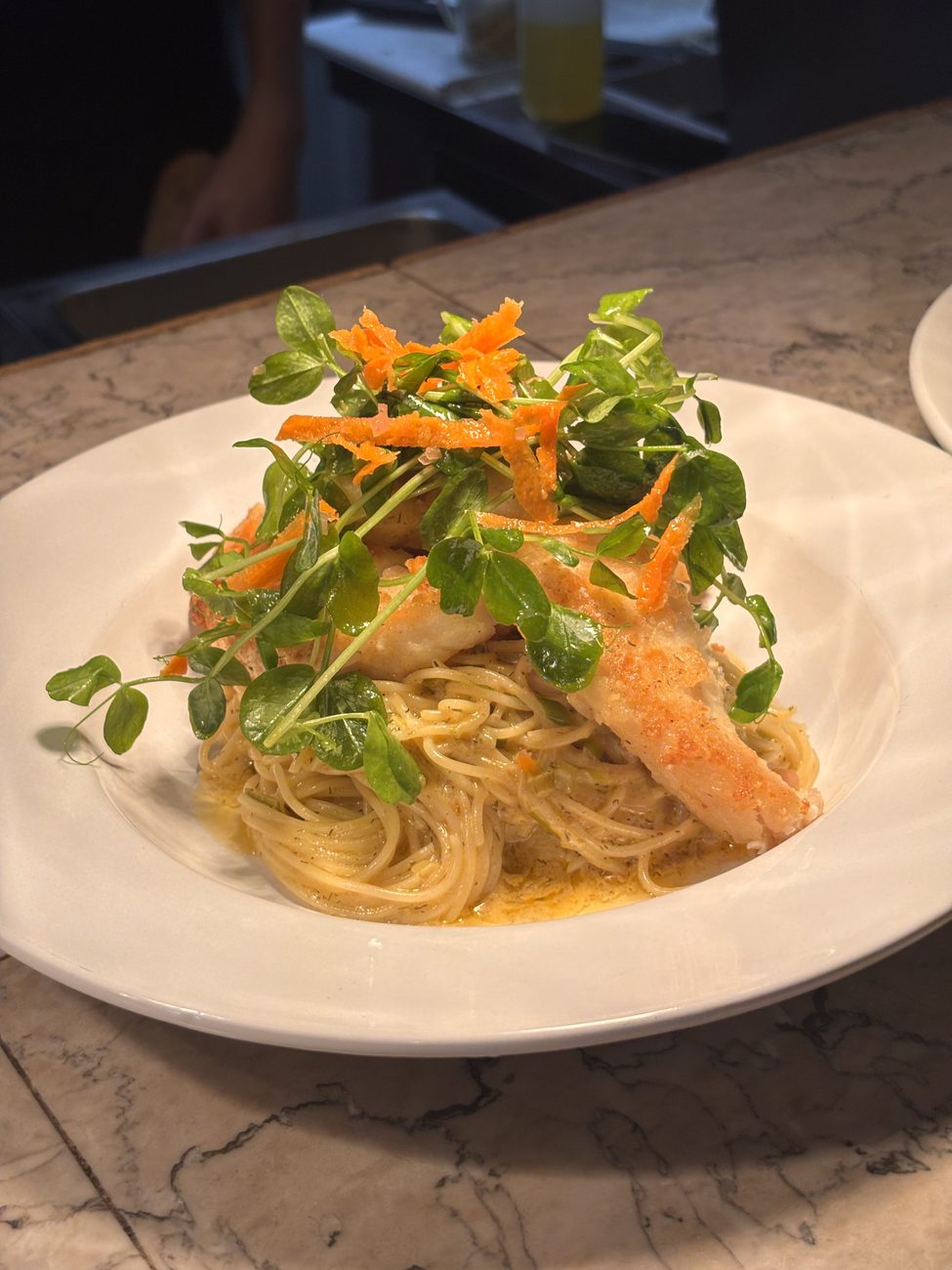 Capellini with a crisp fillet, fresh greens, and shaved carrot