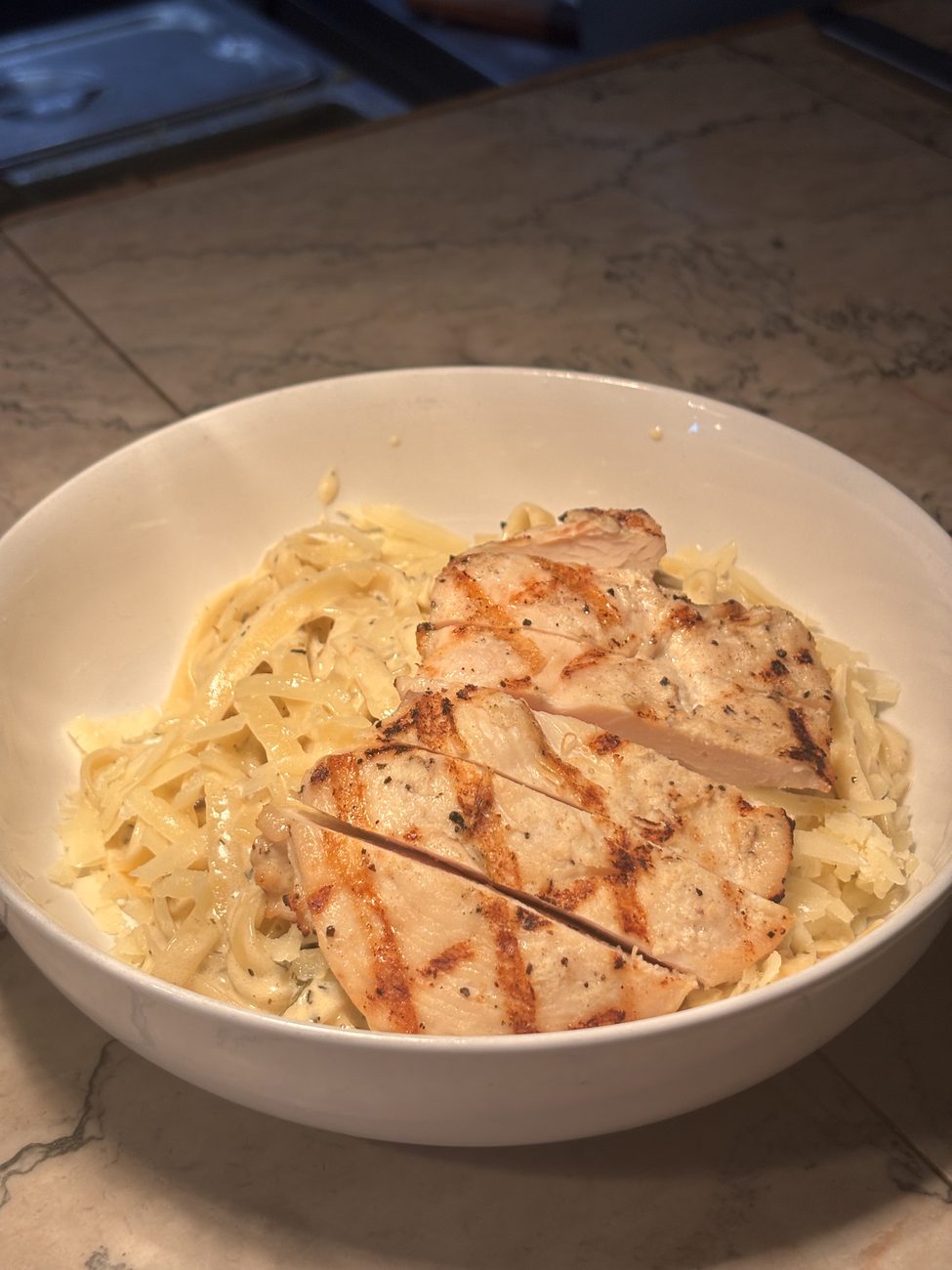 Fettuccine Alfredo topped with sliced grilled chicken