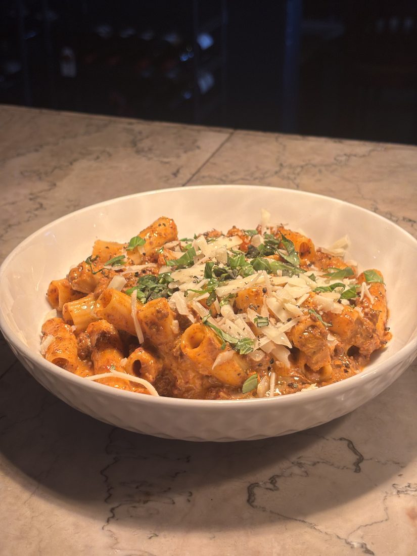 Rigatoni Bolognese topped with shaved parmesan and fresh basil