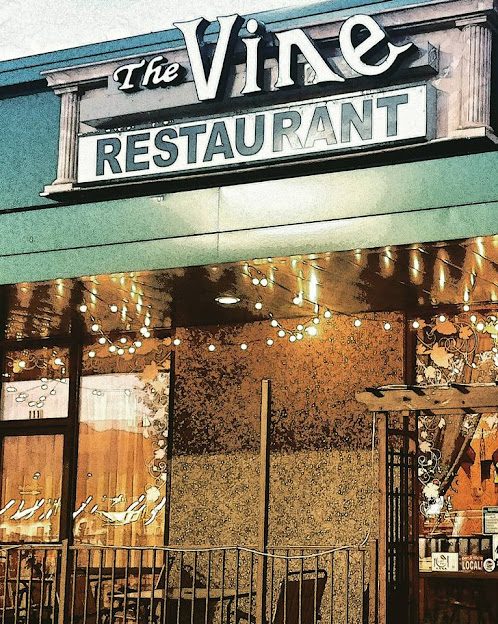 The Vine restaurant storefront in Grants Pass, lit with string lights at dusk